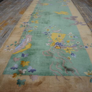 Ornate floral runner rug in mint green and tan laid on distressed wooden flooring.