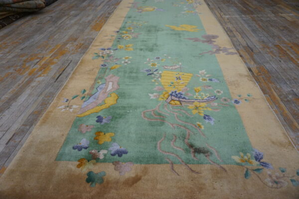 Ornate floral runner rug in mint green and tan laid on distressed wooden flooring.