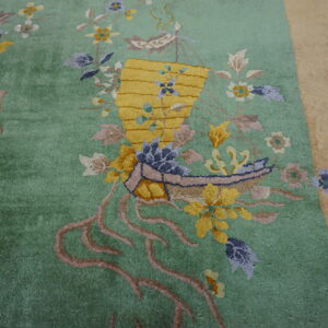 Plush green rug with yellow basket motif and colorful botanical accents bordered by tan on wood floor.