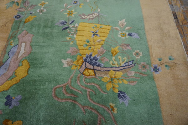 Plush green rug with yellow basket motif and colorful botanical accents bordered by tan on wood floor.