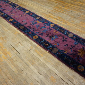 Deep purple runner rug featuring a navy border and blue floral designs rests on worn wooden flooring.