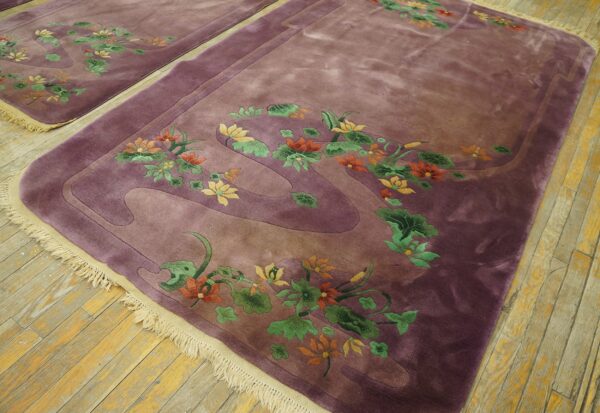 Velvety purple rug featuring carved orange and green floral designs sits on weathered hardwood flooring.