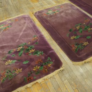 Two plush plum rugs with carved orange, green, and yellow floral patterns on distressed hardwood.