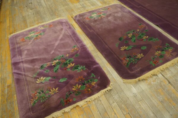 Two plush plum rugs with carved orange, green, and yellow floral patterns on distressed hardwood.