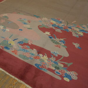 Red field rug with a gray and pink pond motif decorated with multicolored floral blossoms on wood flooring.