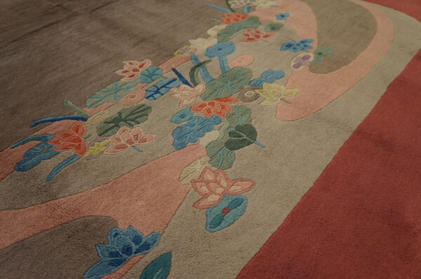 Colorful carved floral pattern overlaying large, flowing bands of pink, tan, brown, and reddish pile.