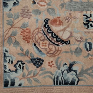 Detailed view of a peach-toned floral rug featuring stylized motifs in blue, rust, and slate gray.