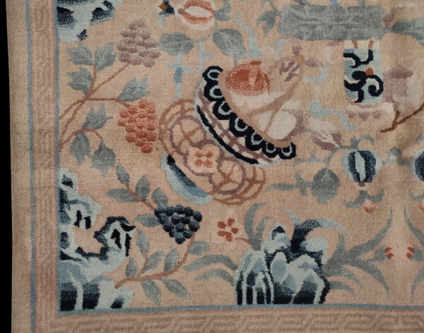 Detailed view of a peach-toned floral rug featuring stylized motifs in blue, rust, and slate gray.
