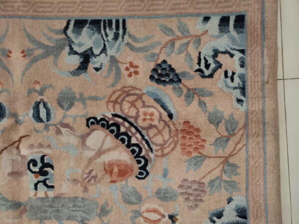 Plush, pale pink rug detail showing intricate blue, gray, and rust botanical patterns on a white tiled floor.