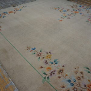 Beige rug with multicolored floral borders and a green line on weathered wooden planks.