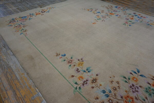 Beige rug with multicolored floral borders and a green line on weathered wooden planks.