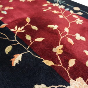 Detailed view of a high-pile rug with maroon and black fields and delicate light-colored floral vines.