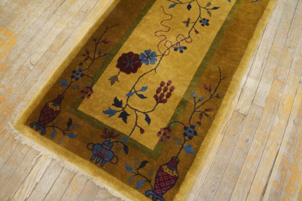 Mustard runner rug features a dark olive border and colorful botanical motifs on light, distressed wood flooring.