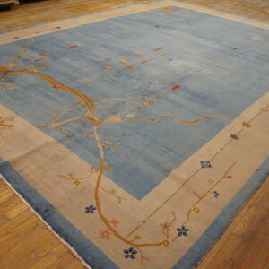 Large blue rug with a golden stylized tree pattern and a thick beige border lies on hardwood floors.