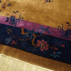 Plush amber rug featuring navy and magenta bordered bands with floral patterns on wood floor.