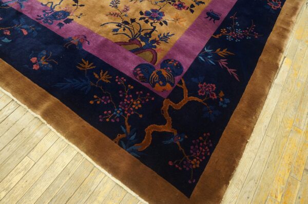 Gold field rug with purple and navy floral borders rests on a distressed pale wood floor.