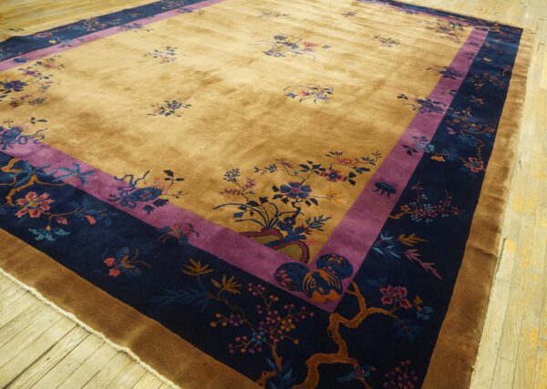 Golden yellow rug with detailed floral patterns and a wide navy and purple border on wood floors.