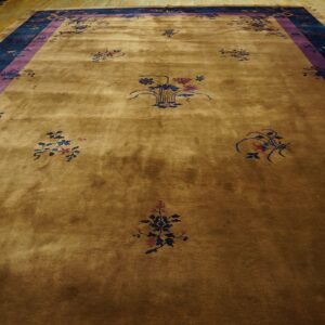 A large golden brown rug with scattered floral patterns and a wide navy and purple border.