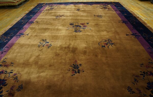 A large golden brown rug with scattered floral patterns and a wide navy and purple border.