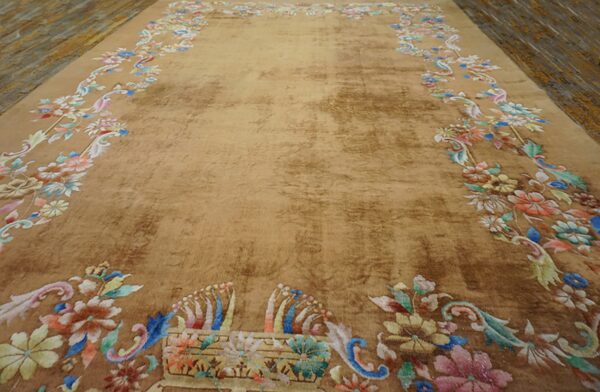 Shimmering tan rug featuring a spacious field and a colorful pastel floral border on distressed wood planks.