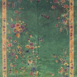 Emerald green rug with an orange border featuring dense, asymmetrical multicolor floral and vine patterns.