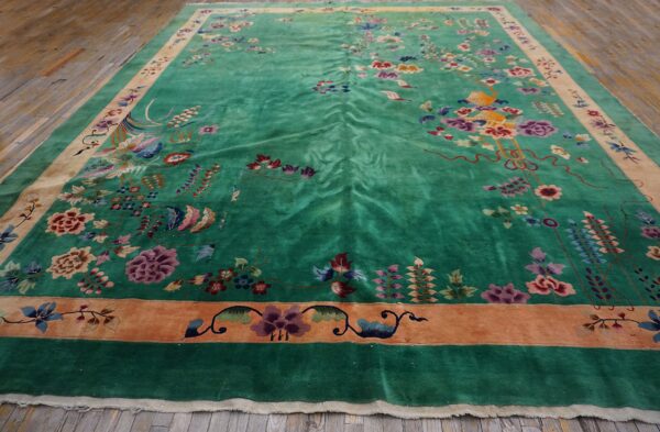 Emerald green area rug with high-luster pile, colorful ornate floral motifs, and terracotta borders on wood flooring.