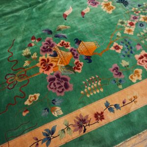Green rug with high sheen featuring detailed purple and orange floral and figural patterns and a tan border.