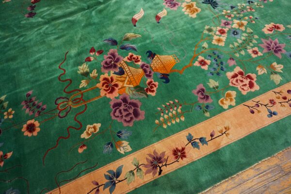 Green rug with high sheen featuring detailed purple and orange floral and figural patterns and a tan border.