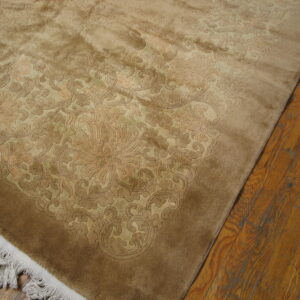 A plush, tone-on-tone brown rug with carved floral patterns rests on distressed plank hardwood floors.