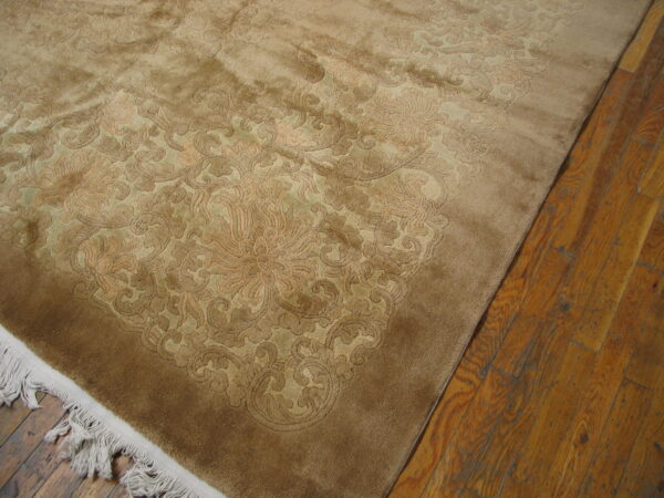 A plush, tone-on-tone brown rug with carved floral patterns rests on distressed plank hardwood floors.
