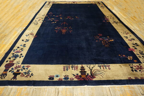 Dark blue rug featuring colorful traditional motifs and a wide golden-tan border, placed on wood plank flooring.