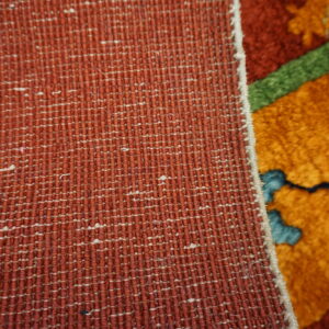 Woven texture in rust and orange contrasts with the thick pile of the colorful floral patterned rug.