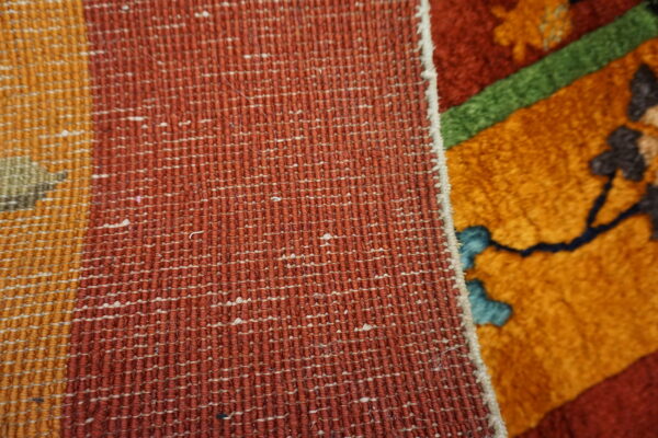 Woven texture in rust and orange contrasts with the thick pile of the colorful floral patterned rug.