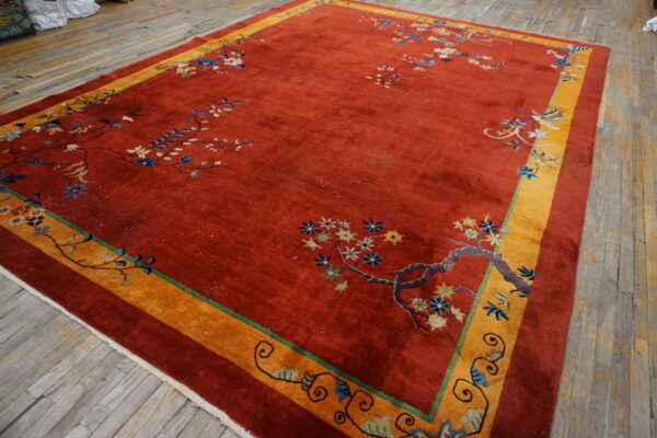 Red pile rug featuring multicolored floral vines and a wide golden border on distressed wooden floors.