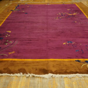 Magenta and brown bordered rug featuring scattered multicolored floral and vine designs on a wooden floor.