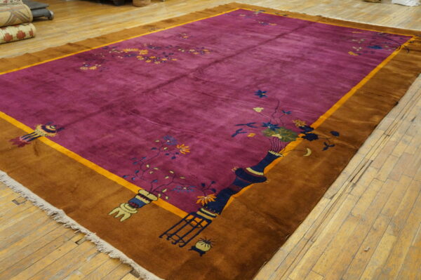 Bright magenta plush rug featuring vase and floral motifs, bordered in golden brown on wood planks.