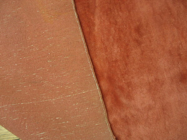 Plush rust colored rug pile folds back to show the tightly woven ribbed underside.
