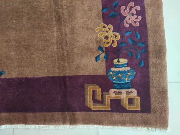 Brown plush rug corner shows a purple border with stylized yellow and pink floral vase motifs.
