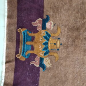 Brown rug with a purple stripe features a gold, teal, and pink stylized figure on white tile flooring.