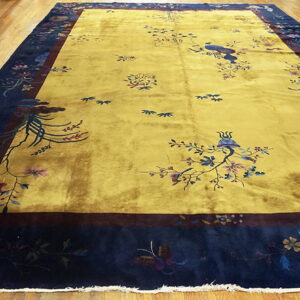 Bright yellow rug with scattered bird and flower patterns and a deep navy border on wood flooring.