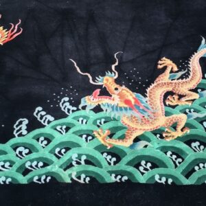 High-pile black rug depicting a colorful dragon over green waves, partially visible on outdoor grass.