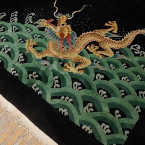 Plush black rug with a detailed gold dragon surrounded by repeating green scalloped wave patterns on wood flooring.