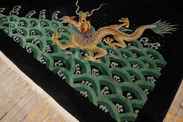 Plush black rug with a detailed gold dragon surrounded by repeating green scalloped wave patterns on wood flooring.