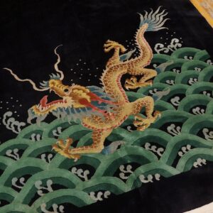Plush black rug with a golden dragon design above green waves, resting on exposed wood floor.
