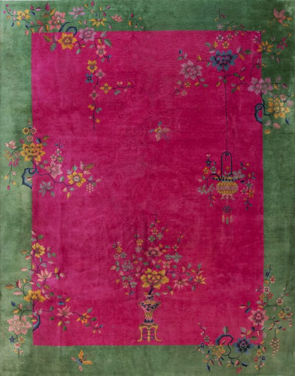 Pink rug with a green border featuring intricate multicolored floral vines, vases, and a hanging lantern.