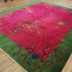 Plush magenta and green rug with scattered colorful floral motifs rests on light wood plank flooring.