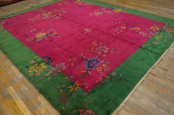Bright magenta rug featuring scattered floral designs and a wide emerald green border on worn wood floors.