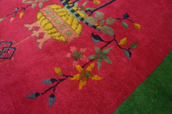 A textured magenta rug with large yellow, pink, and green floral motifs borders a solid green rug.