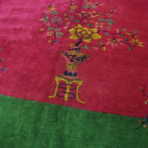 Bright magenta rug with a vase of yellow flowers and branching motifs above a solid green border.