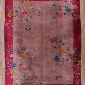 Mauve rug with scattered multi-colored flowers and a wide magenta border on wood flooring.